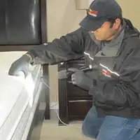 Bed bug inspection technician checking a mattress and bed frame for signs of infestation in Las Vegas, NV