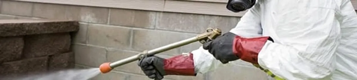 Pest control technician applying exterior insect treatment along a home foundation in Las Vegas, NV